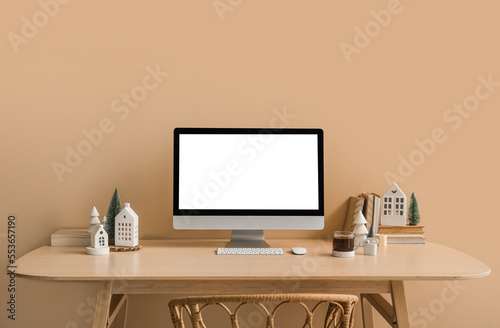 Workplace with computer, candle holders and Christmas trees near beige wall © Pixel-Shot