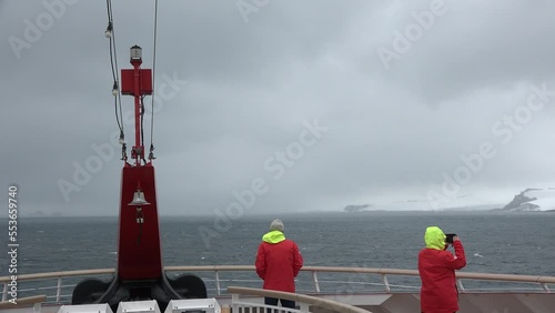 Cruise to Antarctica. Ship, icebergs and tourists passing through Lemaire Channel Antarctica. Cruise ship in front of the glacier, scenic cruising in a sunny day. Climate change. photo