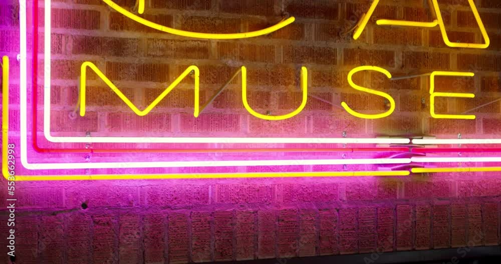 Bright neon Car Museum sign on brick wall above door to cars as camera