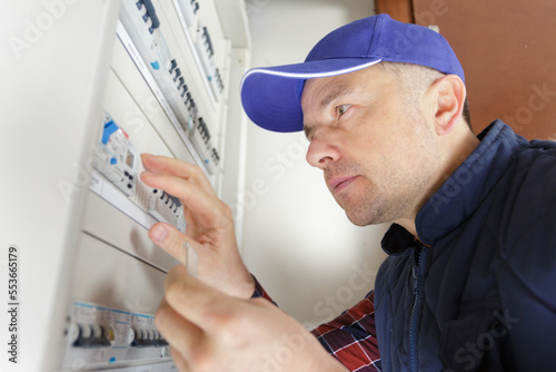 focused electrician by central fusebox photo