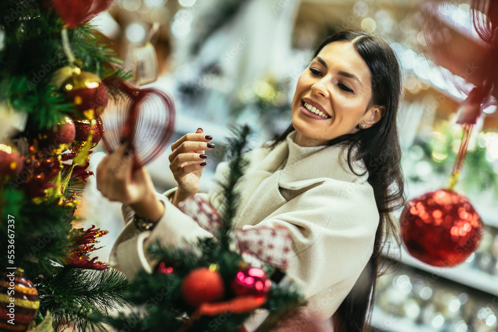 Young woman selecting christmas decorations in decorative goods shop. The girl buys Christmas decorations.