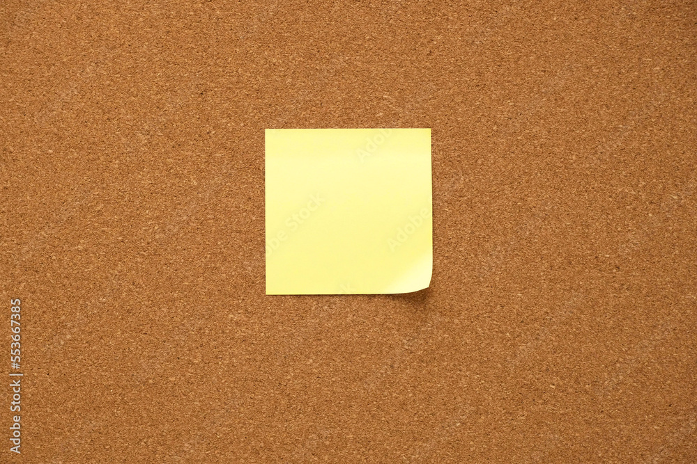 Yellow note paper on a corkboard. Blank sticker for notes with place for your text Yellow note paper on a corkboard. Blank sticker for notes with place for your text