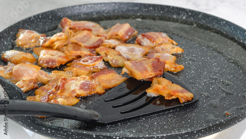 Fried bacon close-up on a frying pan.