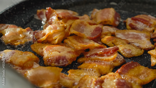 Crispy fried bacon slices on a frying pan