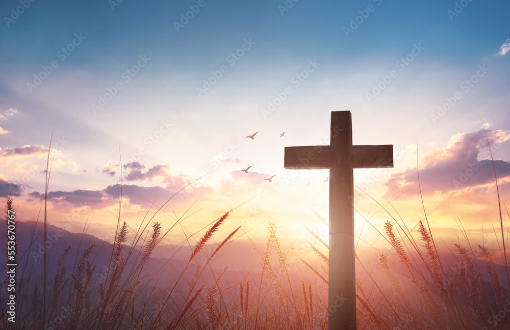 Christian wooden cross on sunset background.