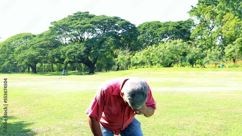 Asian elderly man walking outdoor lawn syour hands from the bright sunlight during the day. feeling unbearable in the hot weather and fainting, dizzy, he hurriedly walked into the shade of the trees. Asian elderly man walking outdoor lawn syour hands from the bright sunlight during the day. feeling unbearable in the hot weather and fainting, dizzy, he hurriedly walked into the shade of the trees.