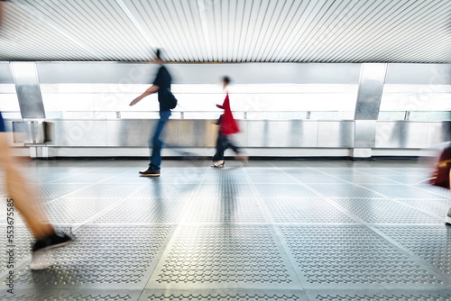 Blurred commuters walking on footbridge