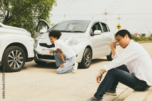 Asian man and african american woman driver sitting stressed serious accident driving illegal traffic damage in front of bumper waiting for insurance company to clear and assess the damage. © ฺฺฺBoonterm