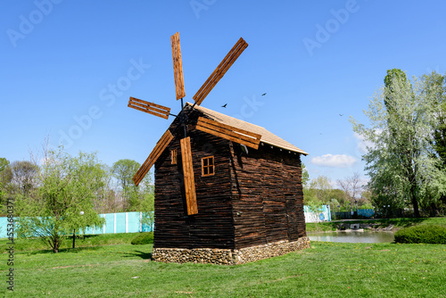 Decorative old wood mill and green grass on a small island on the lake from the Chindiei Park (Parcul Chindiei) in Targoviste, Romania, in a sunny spring day photo