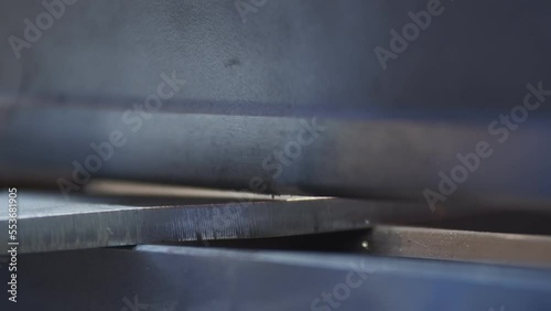 Hydraulic sheet bender slowly bends metal blank laid by the operator during parts manufacturing process on the production area close up with blurred background