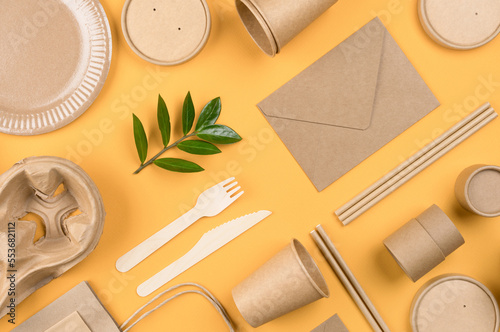 Eco-friendly paper tableware and paper packaging articles over orange background. Street food paper packaging, recyclable paper utensils, zero waste concept. Mockup. Fat lay style