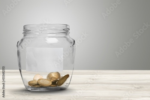 Golden coins in jar on wooden desk