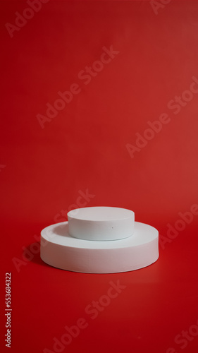 White realistic 3d cylinder pedestal podium on red background. Vector rendering geometric forms. White minimal scene. Stage for showcase, White product display.