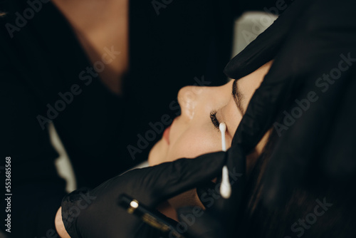 Female face under procedure of eyelashes lamination in beauty salon