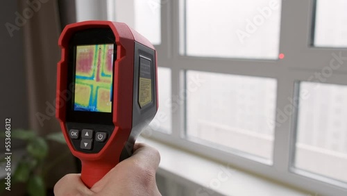 Inspection of a window block inside the room with a thermal imager, searching for heat loss in a building. Thermography concept