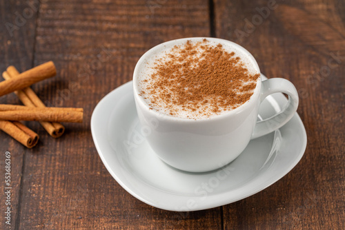 Cinnamon sprinkled salep in a white cup on wooden table photo