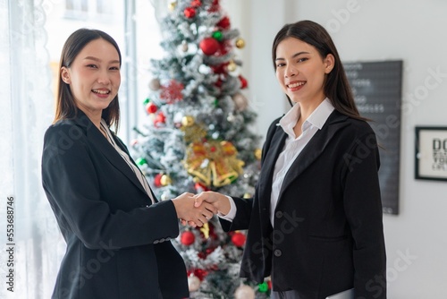 Canvas Print Two young smart beautiful asian lady businesswomen smiling and have a hand shake