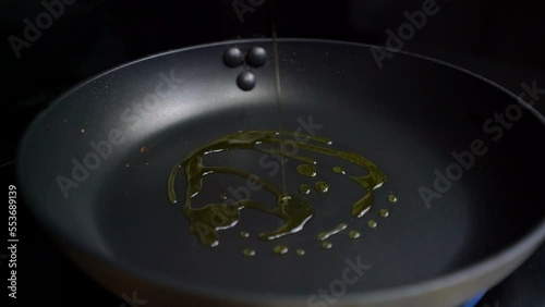 Echando aceite de oliva en sartén caliente photo