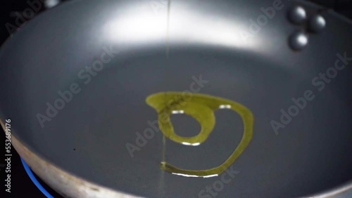 Echando aceite de oliva en sartén caliente photo