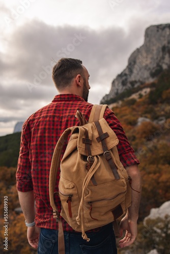The traveler admires the beautiful view from the mountain.
Traveler, tourist in autumn landscape. Mountains and trekking. Concept: Adventure, Vacation, Travel.
