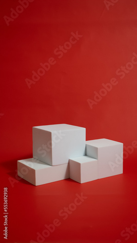 Realistic white cube pedestal podium set in red background. Minimal scene for product display presentation. Stage for showcase.
