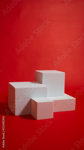 Realistic white cube pedestal podium set in red background. Minimal scene for product display presentation. Stage for showcase.