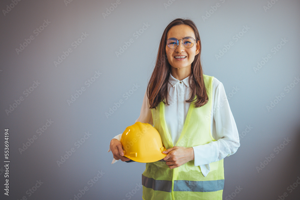 Young female architect standing with her equipment in her office. Construction girl working concept. Portrait of smiling architect with blueprints in office. Female Asian architect smiling to camera Young female architect standing with her equipment in her office. Construction girl working concept. Portrait of smiling architect with blueprints in office. Female Asian architect smiling to camera