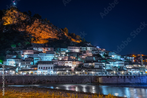 Evening view to Berat, historic city in the south of Albania at night with all lights flashing and white houses gathering on a hill. Captured during blue hour with the sky full of stars.