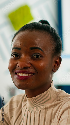 Black manager woman looking at camera smiling, sitting at conference desk during brainstorming. Diverse entrepreneur working in professional start up financial business ready for strategy meeting