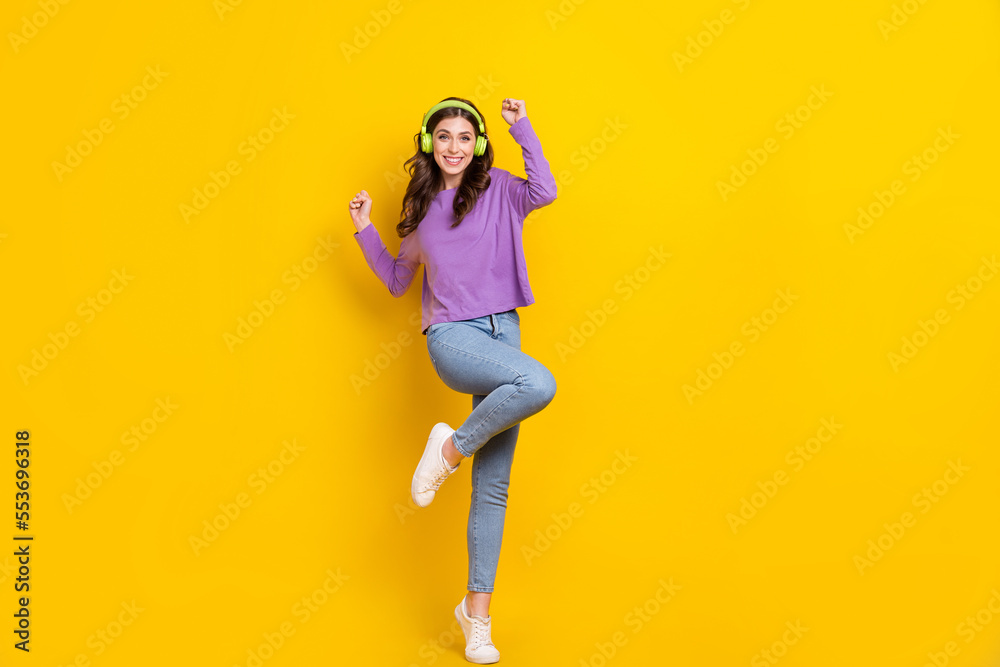 Full size photo of positive pretty girl raise fists enjoy new playlist isolated on yellow color background Full size photo of positive pretty girl raise fists enjoy new playlist isolated on yellow color background