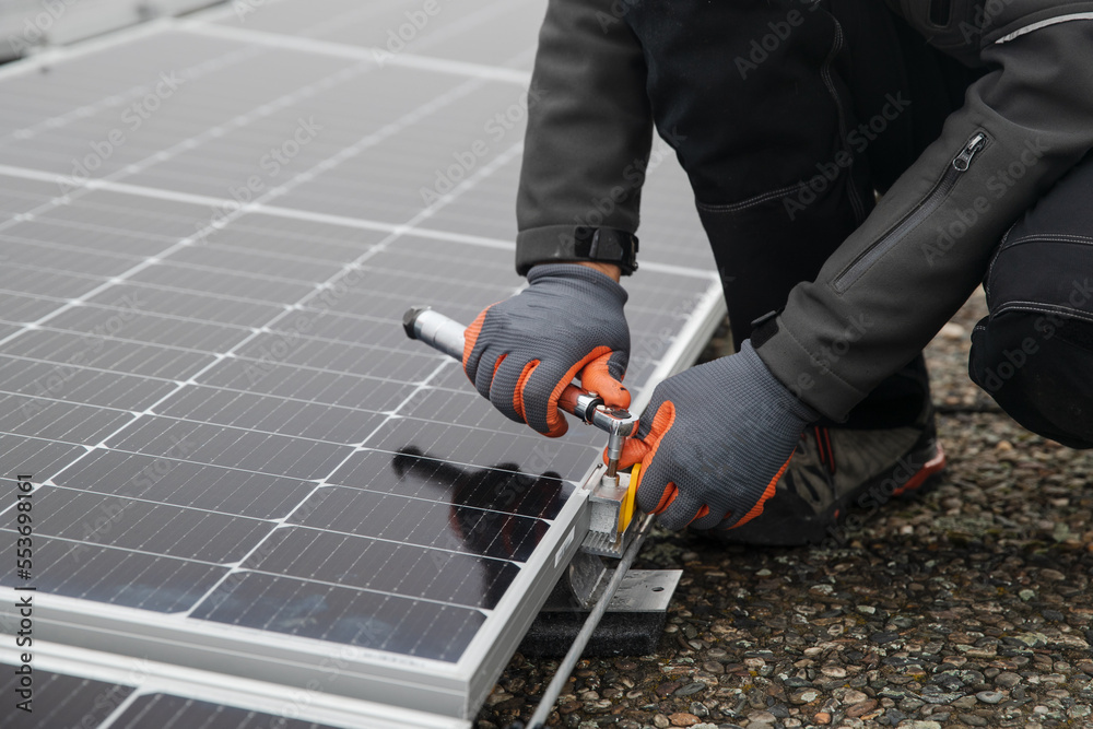 Worker installing solar photovoltaic panel system on roof of a building. Worker installing solar photovoltaic panel system on roof of a building.