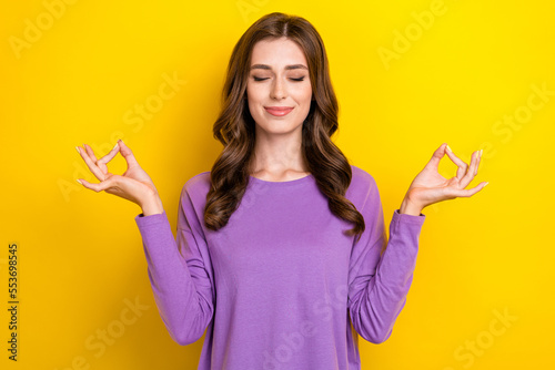 Photo of young attractive chilling woman closed eyes wear purple pullover balance asana meditation after work isolated on yellow color background