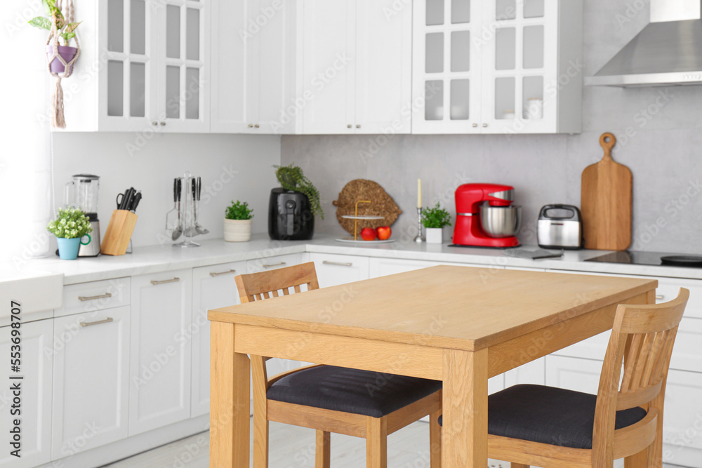 Stylish wooden table with chairs in kitchen. Interior design Stylish wooden table with chairs in kitchen. Interior design