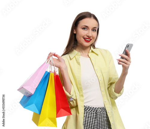Stylish young woman with shopping bags and smartphone white background