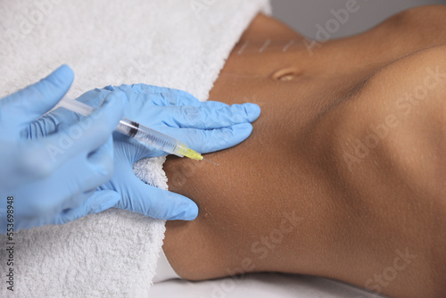 Young woman getting belly injection in salon, closeup