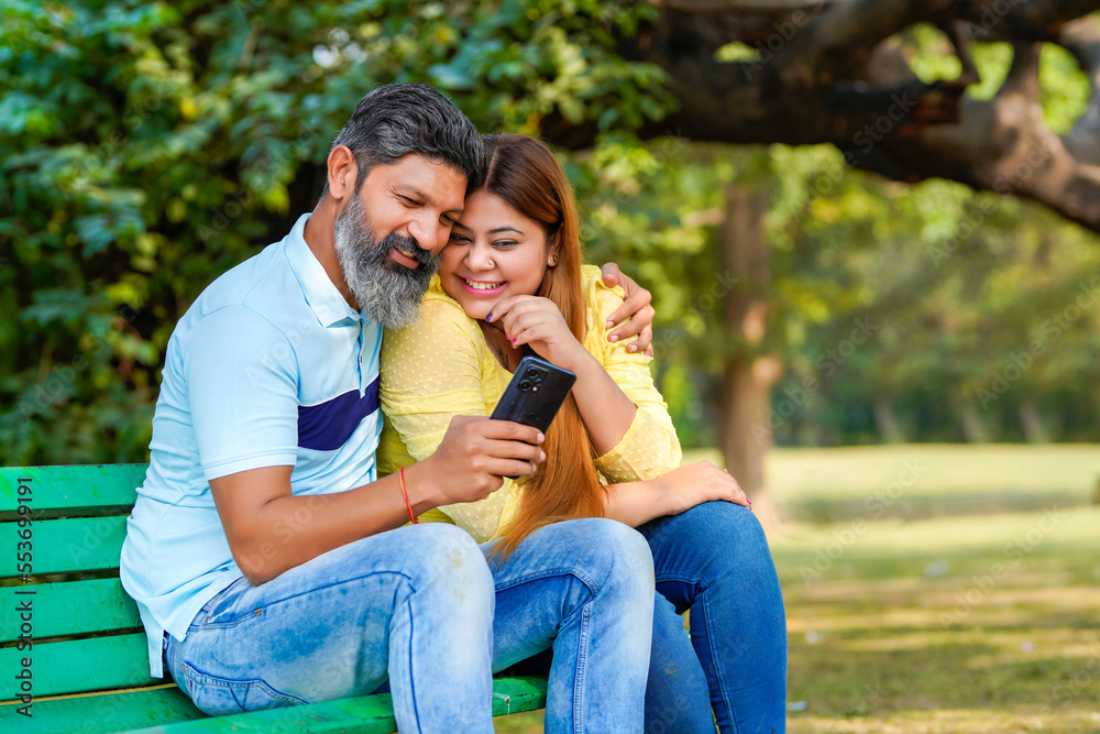 Fototapeta premium Indian man and woman watching some detail in smartphone at park.