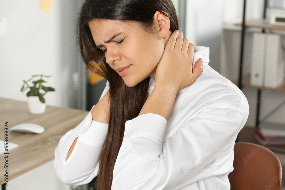 Young woman suffering from neck pain in office Young woman suffering from neck pain in office
