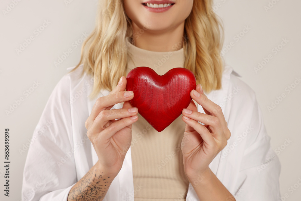 Happy volunteer holding red heart with hands on light background, closeup Happy volunteer holding red heart with hands on light background, closeup