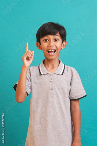 Asian little boy doing gesture of an idea with finger pointed up isolated over green background