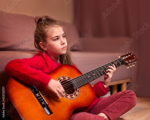 teen girl playing guitar sitting on the floor
