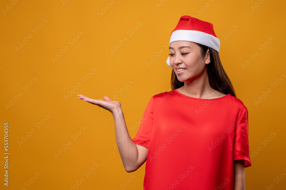Cute young woman in santa hat on a yellow background Cute young woman in santa hat on a yellow background