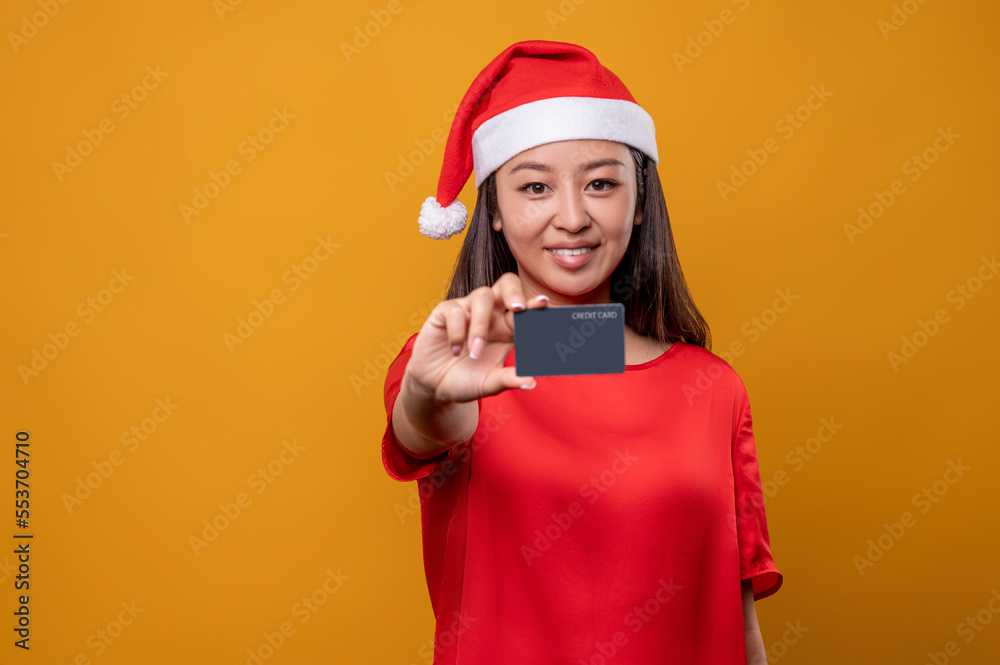 Cute woman in red dress and santa holding a credit card in hand Cute woman in red dress and santa holding a credit card in hand