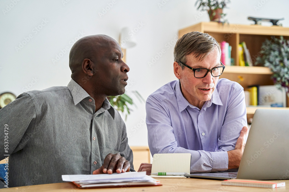 Two mature small company owners discussing business issues in their office Two mature small company owners discussing business issues in their office