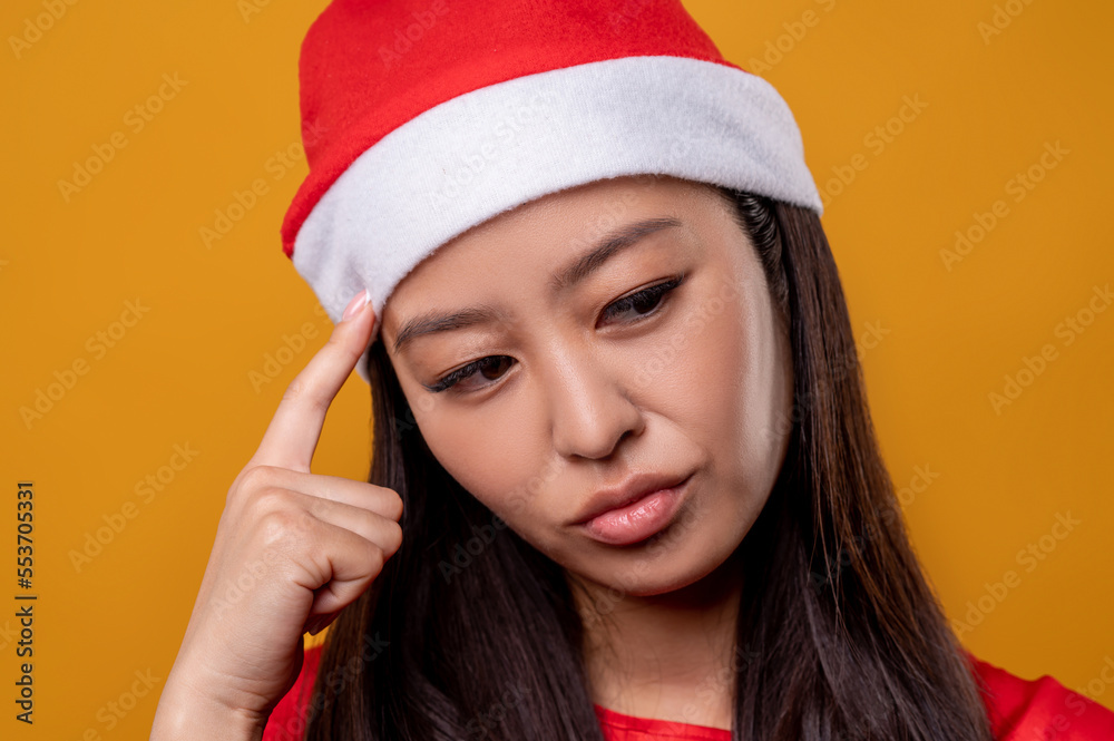 Pretty young woman un santa hat looking thoughtful Pretty young woman un santa hat looking thoughtful