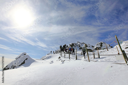 추운 겨울에 눈 덮인 높은 산을 오르는 사람들