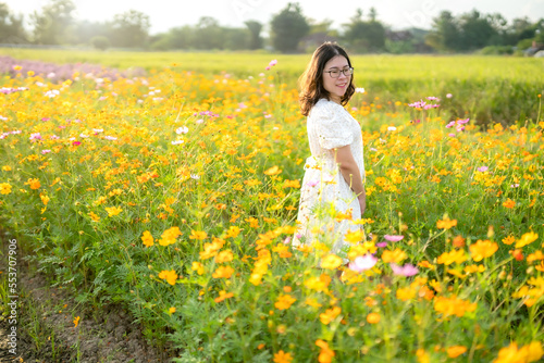 Portrait of asian Young woman happy traveler with white dress enjoying in Yellow and pink sulfur Cosmos flowers blooming field in the nature garden of in Chiang Mai,Thailand,travel relax vacation © Thinapob