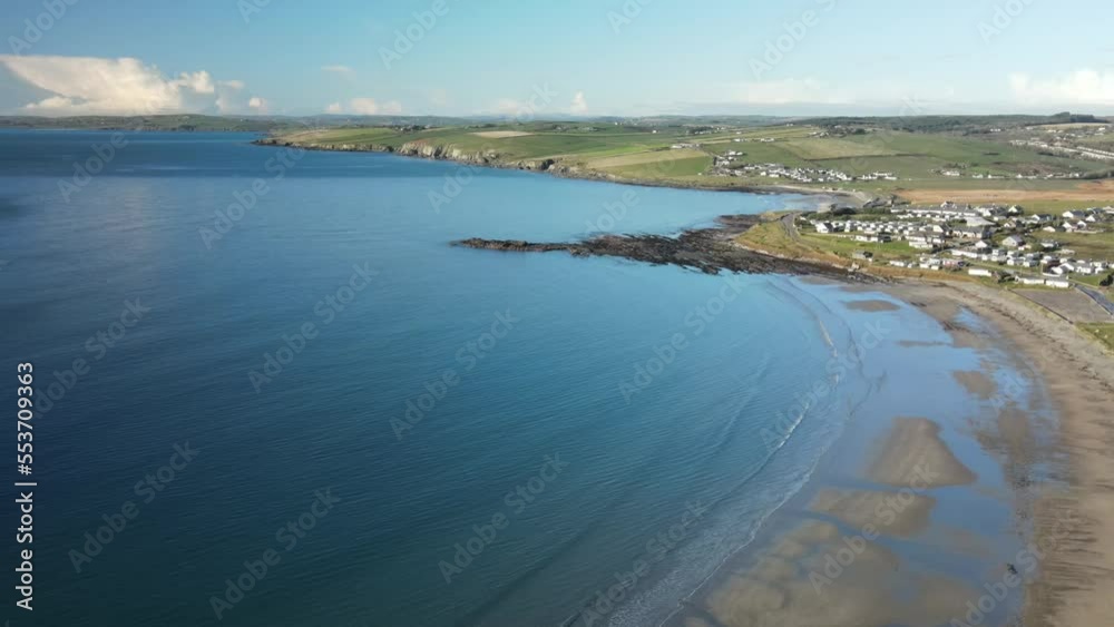 Winter calm blue ocean and coastal sandy beach with small village in the distance, Ireland, aerial, Winter calm blue ocean and coastal sandy beach with small village in the distance, Ireland, aerial,