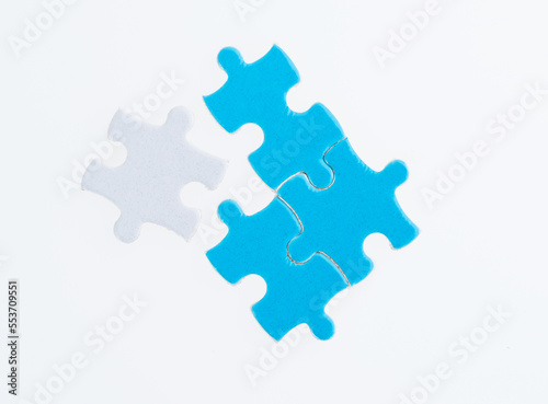 Three blue and one white puzzle pieces on white background