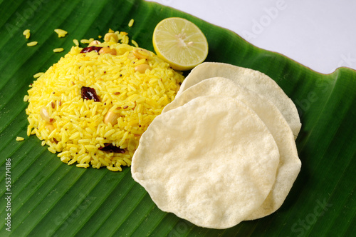 Lemon Rice or fodnicha bhat is South Indian turmeric rice or maharashtrian recipe using leftover rice garnished with nuts curry leaves and lemon juice photo