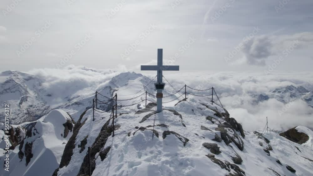 Close up drone shot of summit cross on snowy mountain peak of Kitzsteinhorn during sunny day in Austria Close up drone shot of summit cross on snowy mountain peak of Kitzsteinhorn during sunny day in Austria